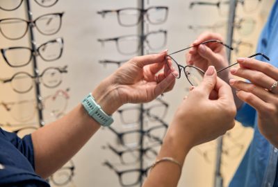 Close-up view of hands adjusting and examining a pair of eyeglasses in an optical shop