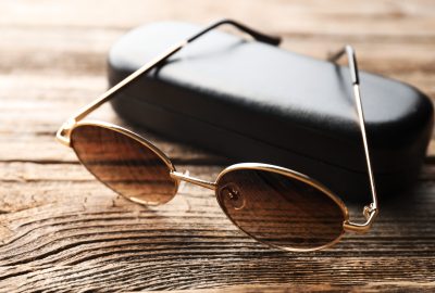 Stylish sunglasses and case on wooden table, closeup