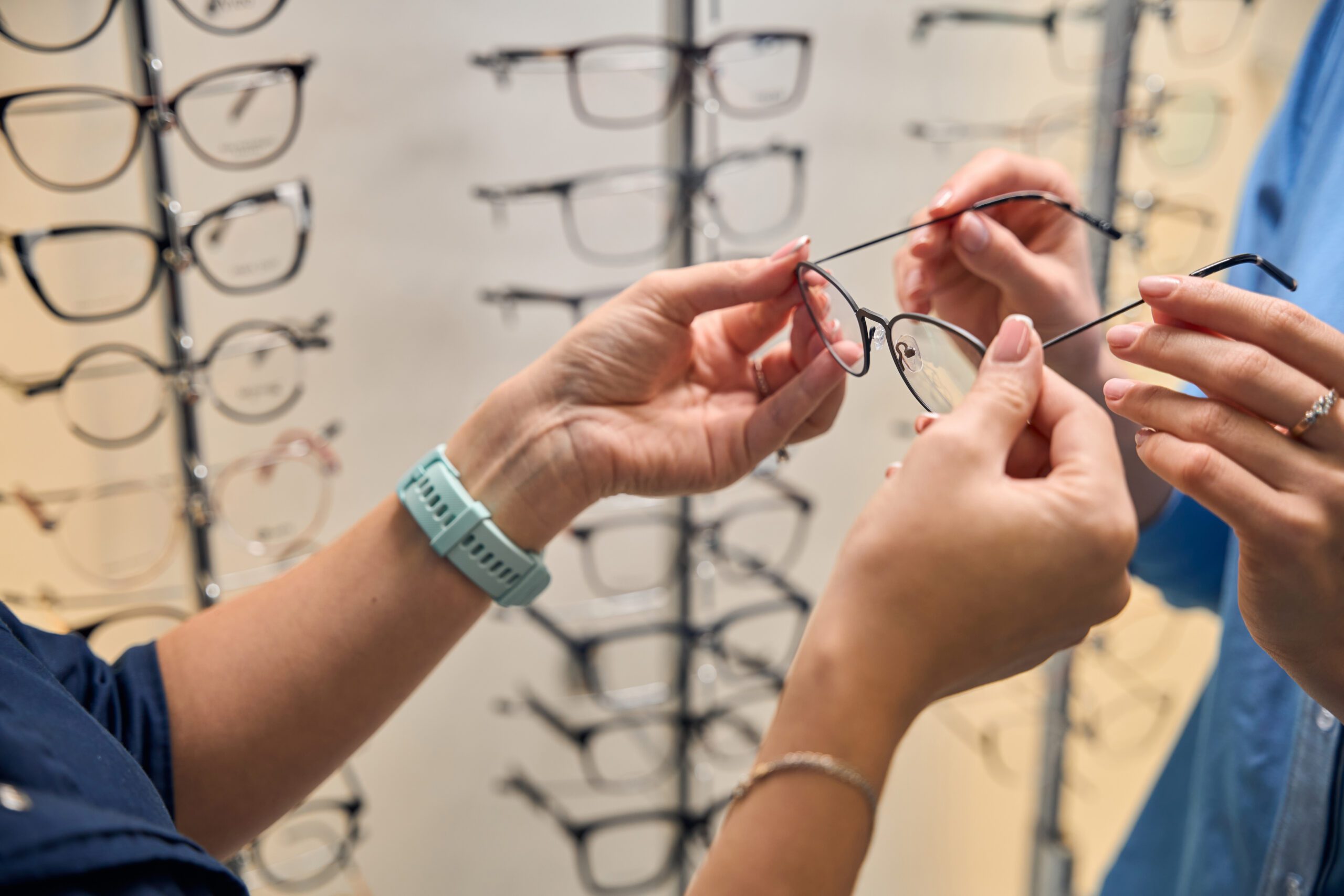 Close-up view of hands adjusting and examining a pair of eyeglasses in an optical shop